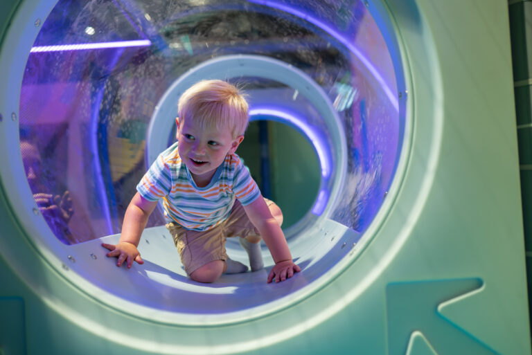 Pojke som utforskar en tunnel i Jumpy lekland